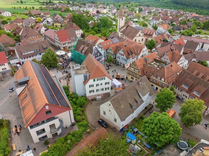 Aerial view of a village with historic architecture, numerous red roofs and a central church,