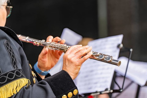 Musician playing the flute during a performance, in uniform with sheet music, family party in