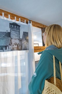 Woman looking at historical photograph in a room with wooden elements, family celebration in