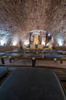Vaulted cellar with sculpture, surrounded by stone walls and illuminated, sacred ambience, registry