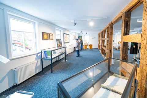 White modern exhibition space with works of art and few visitors, family party in Neubulach,