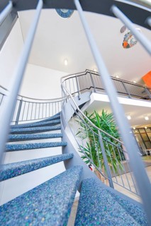 Modern spiral staircase with blue steps and a stylish banister in a bright interior, town hall,