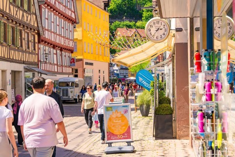 Lively street with half-timbered houses and shops, full of pedestrians on a sunny day, Calw railway