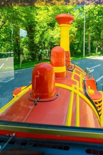 Red and yellow locomotive travelling on a green, sunny road, Calw railway station festival, Black