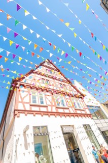 Half-timbered house decorated with colourful flags under a blue sky, Calw station festival, Black