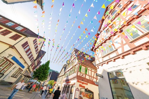 Colourful pennants span a picturesque street with half-timbered houses, Calw station festival,