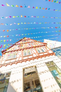 Half-timbered house decorated with colourful pennants under a clear blue sky, Calw station