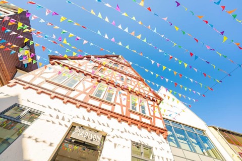 Medieval half-timbered house with colourful pennants in front of a blue sky, Calw station festival,