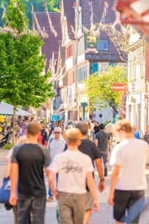 Lively city street with people and sun in summer, Calw railway station festival, Black Forest,