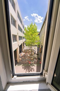View from a window onto a courtyard with a tree, surrounded by buildings under a blue sky, Calw