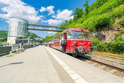 Red train stands on the platform in bright daylight, Calw railway station festival, Black Forest,