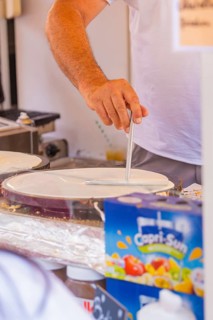 Person preparing crepe batter at a market stall, Calw railway station festival, Black Forest,
