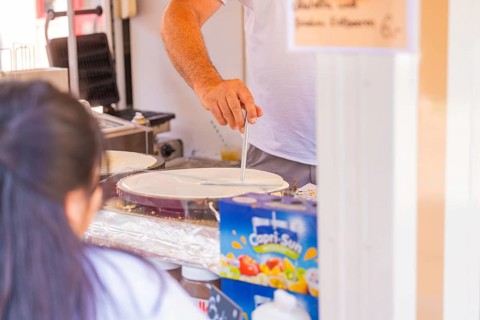 Man preparing crepes in a market stall with Capri-Sun in the background, Calw railway station