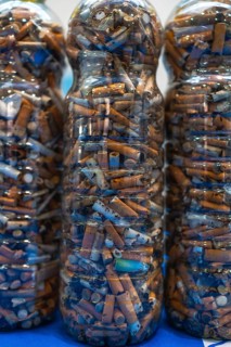 Plastic bottles filled with cigarette butts collected during cleanup efforts on a beach,