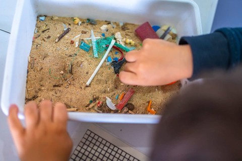 Young student analyzing a sand sample containing microplastics, highlighting the growing concern of