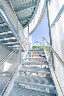 Modern metal staircase structure with glass walls and plenty of daylight, Zob extension with bridge