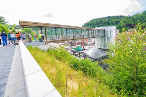 People standing on a modern bridge with city and green views, Zob extension with bridge