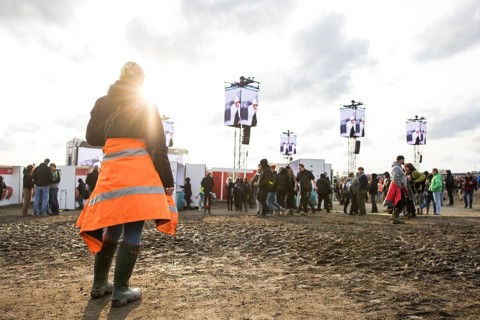 A festival visitor stands in front of a muddy area in the evening sun at the Rock am Ring Festival