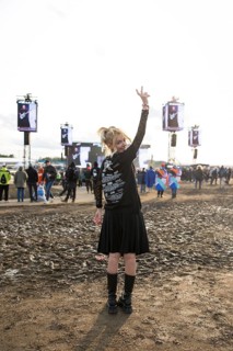 A festival visitor from Turkey poses in front of a muddy area in the evening sun at the Rock am