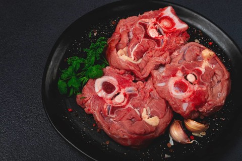 Raw steak, calf's neck on the bone, fresh meat, on a black plate, top view, no people