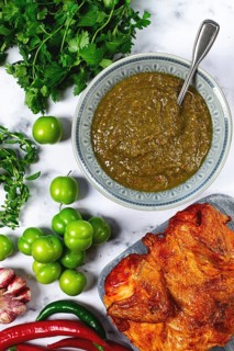 Tkemali sauce, made from green cherry plum, with ingredients on the table, tobacco chicken, top