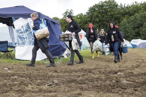 Festival visitors carry their luggage through mud on a campsite at the Rock am Ring festival on