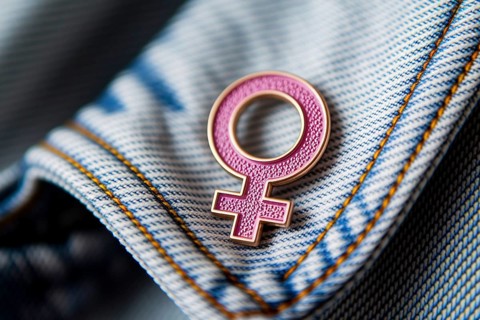Pink female gender symbol pin attached to denim jacket, symbol of feminism and identity. Generative
