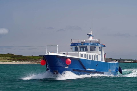 Large blue boat in motion on wavy sea with red buoy, passenger ferry, Isles of Scilly, Cornwall,