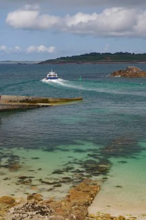 Small boat sailing through a rocky inlet on the way to the open sea, St Agnes, Isles of Scilly,