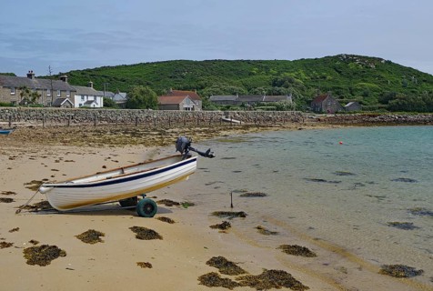 Small boat on a trailer on a quiet sandy beach near residential houses, Tresco, Isles of Scilly,