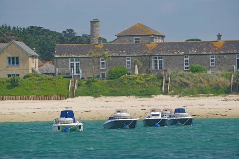 Four small boats close to the beach in front of traditional houses in an idyllic setting, Tresco,