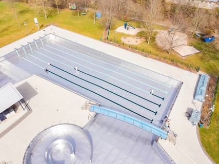 Aerial view of an empty outdoor pool with swimming pool and surrounding lawn in autumnal