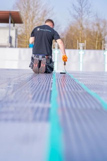 A worker kneels and works with tools on pool tiles, renovation of the swimming lines, Calw