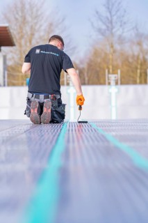 Rear view of a worker on a construction site applying strip paint with a roller, renovation of the