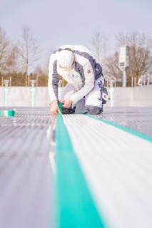 A worker kneels on the ground and precisely sticks on a green tape, renewal of the swimming lines,
