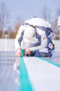 Close-up of a worker applying adhesive tape with a concentrated look on his face, renewing the