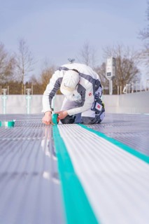 A worker on the construction site sticks a green tape along the floor, renewal of the swimming