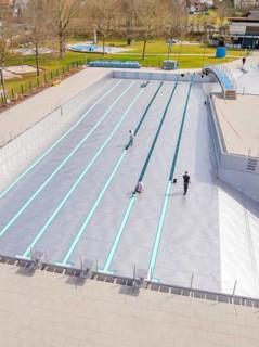 People working at an empty swimming pool in a green environment, renewal of the swimming lines,