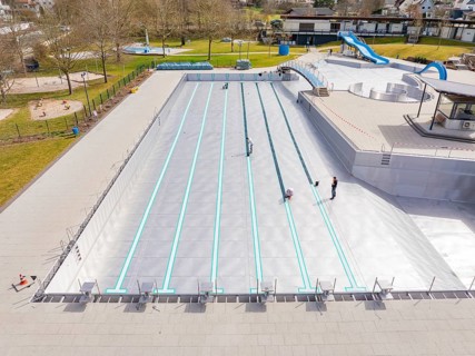 High-angle view of a swimming pool under construction with workers and trees, renewal of the