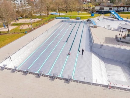 Swimming pool with workers and green surroundings in the distance, renewal of the swimming lines,
