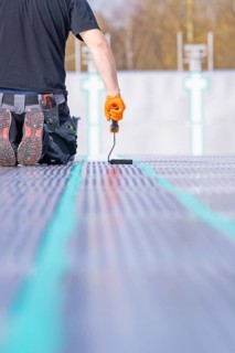 A worker kneels on the ground and applies strip paint with a paint roller, renovation of the