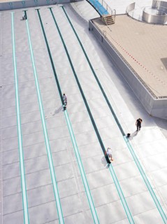 Several people working in an empty swimming pool with metal walls, renovation of the swimming