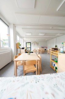 Bright kindergarten room with wooden furniture and large windows, transitional containerised