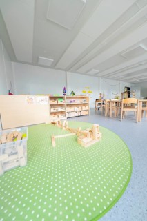 Kindergarten with green carpet and building blocks on the floor, transitional containerised daycare