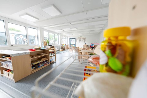 Bright kindergarten room with wooden furniture and toys, light-flooded and modern design,