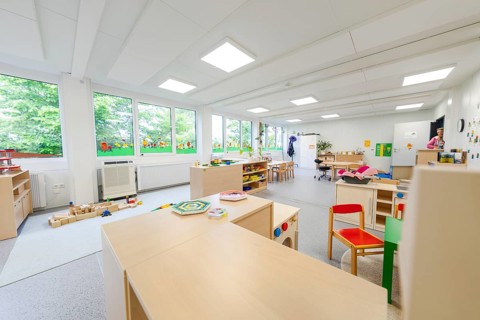 Large, open kindergarten room with windows and child-friendly furniture, transitional containerised