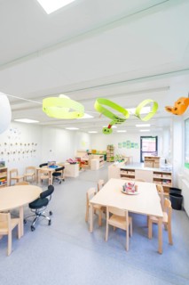 Open school classroom with paper artwork and wooden furniture, transitional containerised daycare