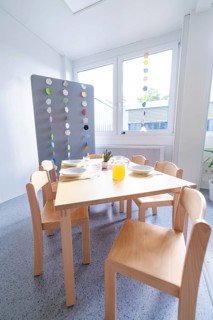 Modern dining area with wooden furniture and colourful window decorations, transitional daycare
