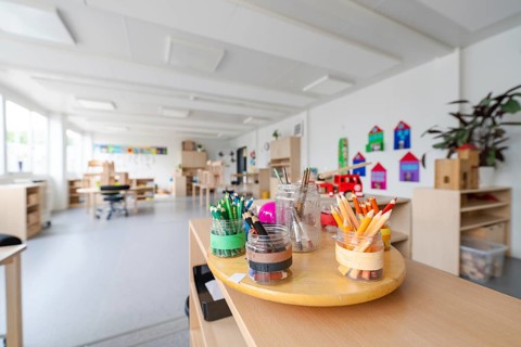 Art area with neatly arranged coloured pencils on a table, transitional daycare centre in container