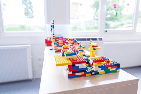 Colourful Lego models on a table in front of a sunny window, transitional daycare centre in